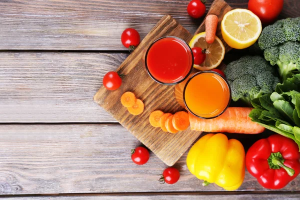 Karotten- und Tomatensaft in Gläsern und frischem Gemüse auf Holzgrund — Stockfoto