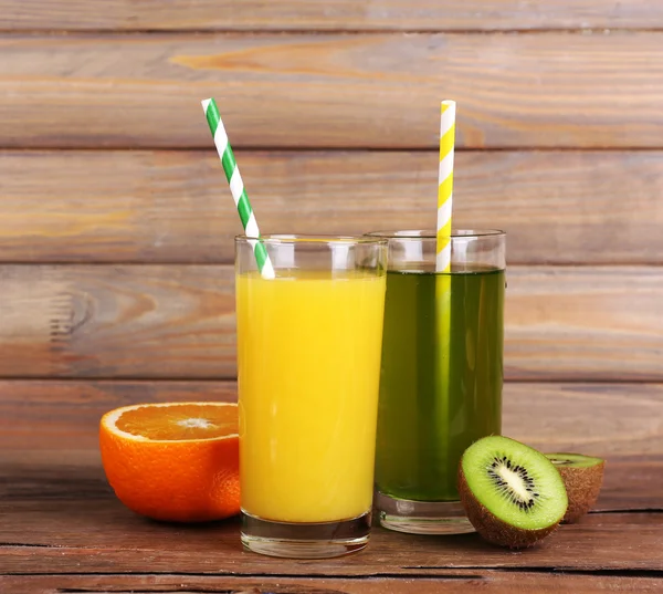 Orange and kiwi juice and fresh fruits on wooden table on wooden wall background — Stock Photo, Image