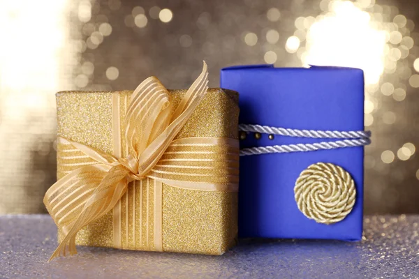 Blauwe en gouden geschenkdozen op tafel op glanzende achtergrond — Stockfoto