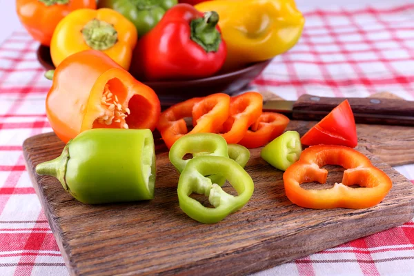 Pepper on plate and on cutting board on fabric background — Stock Photo, Image