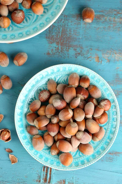 Hazelnuts on plates on wooden background — Stock Photo, Image