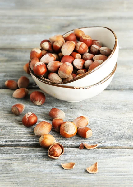 Hazelnuts in bowl on wooden background — Stock Photo, Image