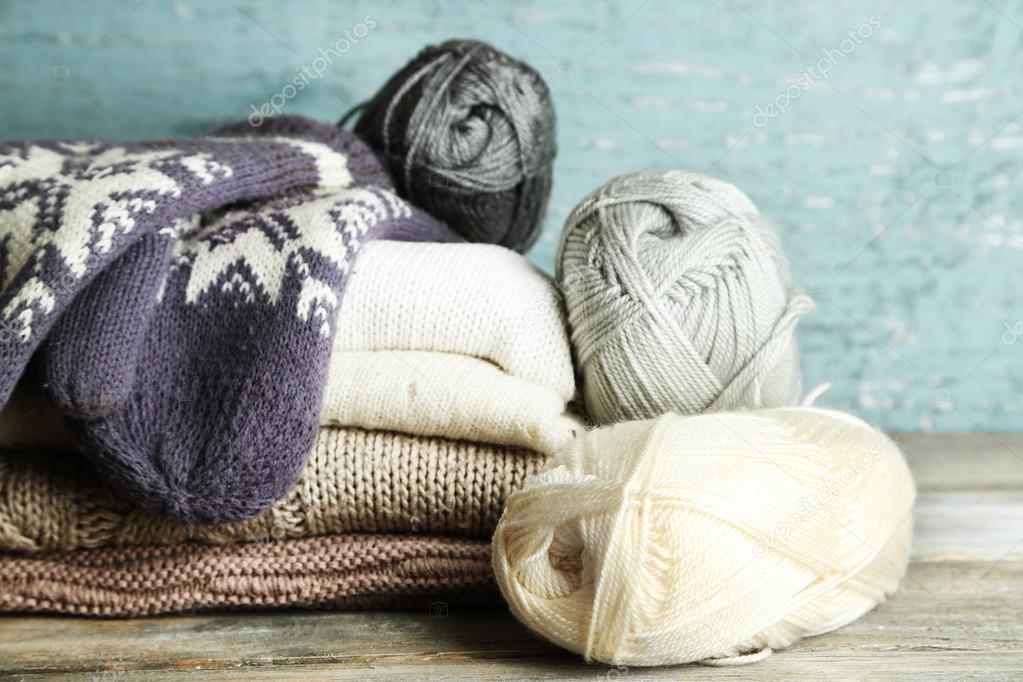 Knitting clothes, yarn and mittens, on wooden background