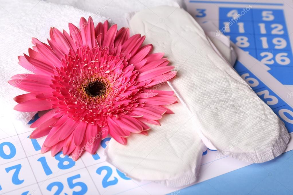 Sanitary pads and pink flower on blue calendar background