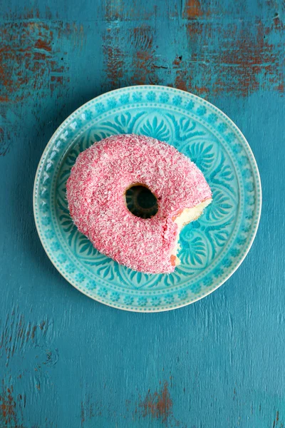 Bitten delicious donut on plate on wooden table close-up — Stock Photo, Image