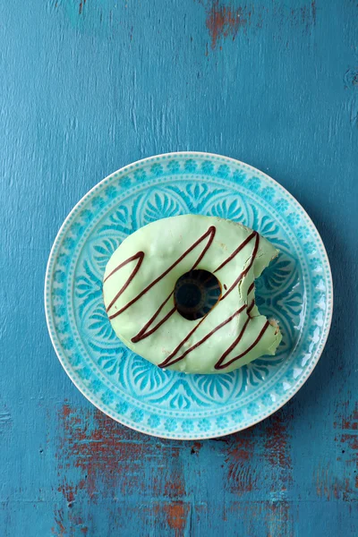 Bitten delicious donut on plate on wooden table close-up — Stock Photo, Image