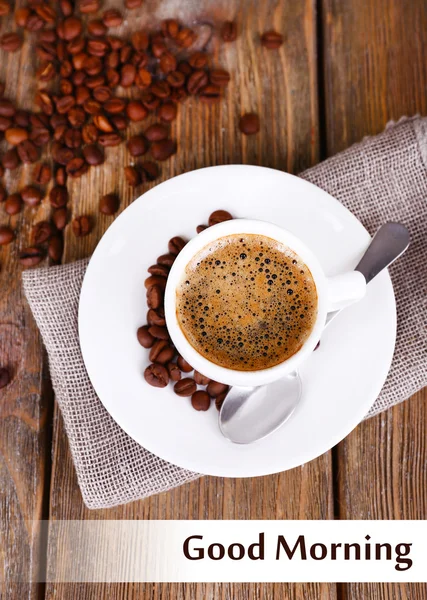 Cup of coffee with milk and coffee beans on napkin on wooden background — Stock Photo, Image
