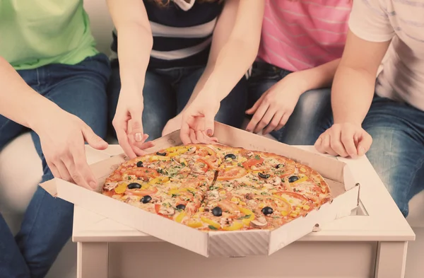 Grupa młodych przyjaciół jeść pizzę w salonie na kanapie — Zdjęcie stockowe