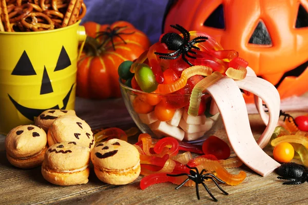 Композиция на Хэллоуин со сладостями на деревянном столе — стоковое фото