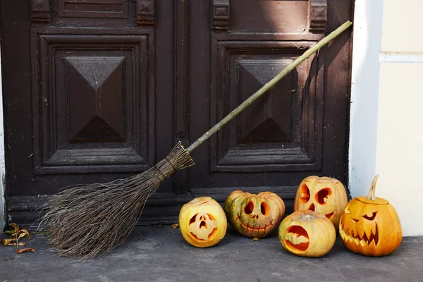 Calabaza y escoba para Halloween en el fondo de la puerta de madera vieja — Foto de Stock