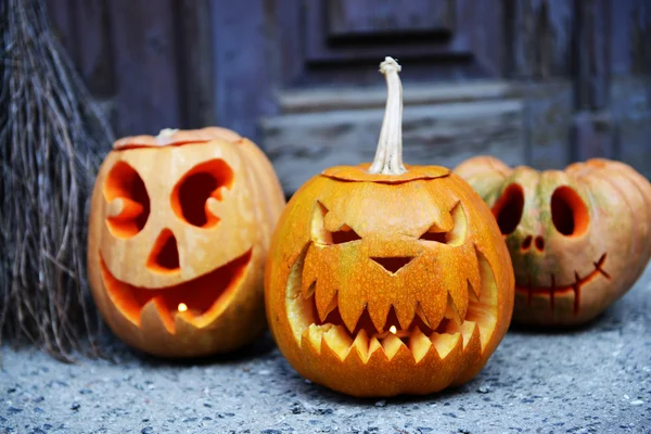 Calabaza y escoba para Halloween en el fondo de la puerta de madera vieja — Foto de Stock