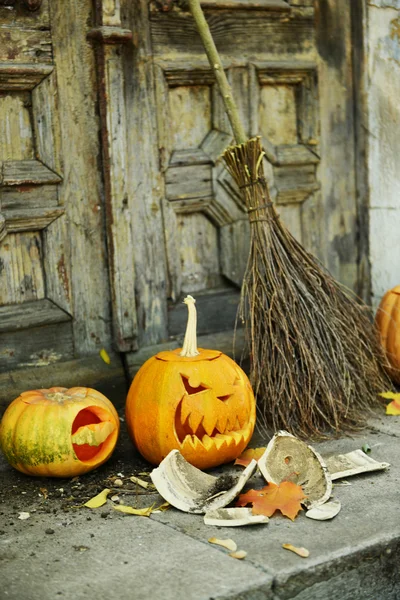 Pompoen en bezem voor vakantie Halloween op oude houten deur achtergrond — Stockfoto