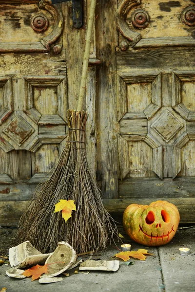 Dýně a koště pro svátek Halloween na pozadí staré dřevěné dveře — Stock fotografie