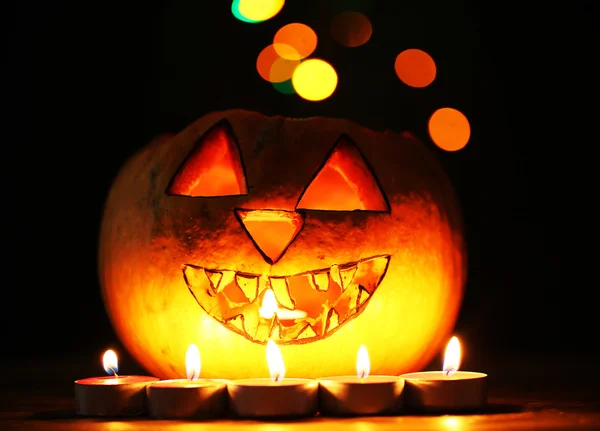 Abóbora de Halloween e velas na mesa em fundo de cor escura com luzes multicoloridas — Fotografia de Stock