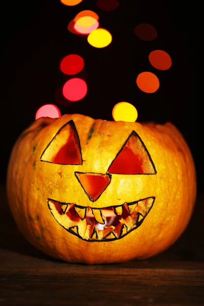 Halloween pumpa på bordet på mörk färgbakgrund med multicolor lampor — Stockfoto