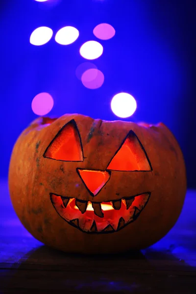Halloween pumpa på bordet på mörk färgbakgrund med multicolor lampor — Stockfoto