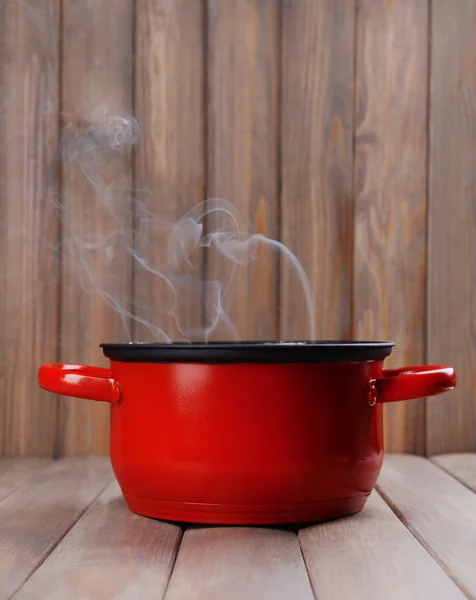 Kookpot met stoom op tafel op houten achtergrond — Stockfoto