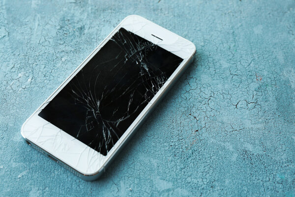 Современный мобильный телефон со сломанным экраном на деревянном фоне
