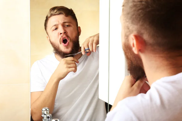 Young man shaving his beard in bathroom — Stock Photo, Image