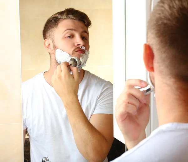 Jovem barbear sua barba no banheiro — Fotografia de Stock