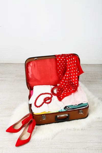 Vestiti femminili in valigia vecchia su sfondo chiaro — Foto Stock