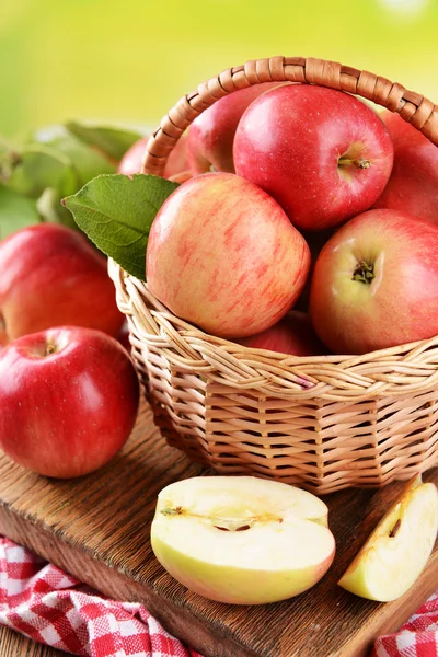 Manzanas dulces en canasta de mimbre sobre mesa sobre fondo brillante —  Fotos de Stock