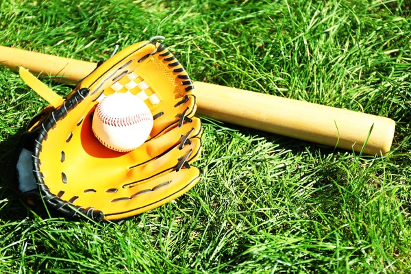 Baseball bat, ball and glove on green grass background — Stock Photo, Image