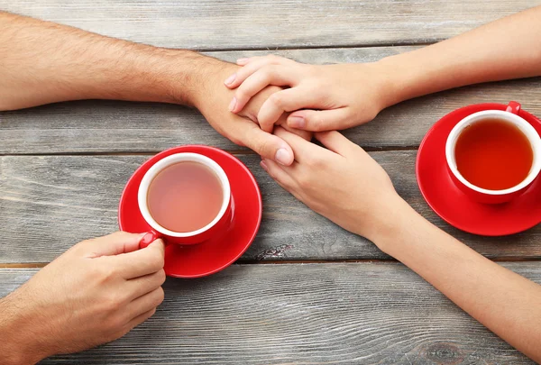 Loving couple with hot drinks on table — Stock Photo, Image