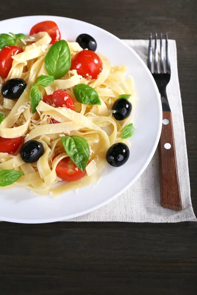 Espaguetis con tomates, aceitunas y hojas de albahaca — Foto de Stock