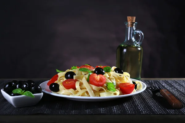 Spaghetti with tomatoes, olives and basil leaves — Stock Photo, Image