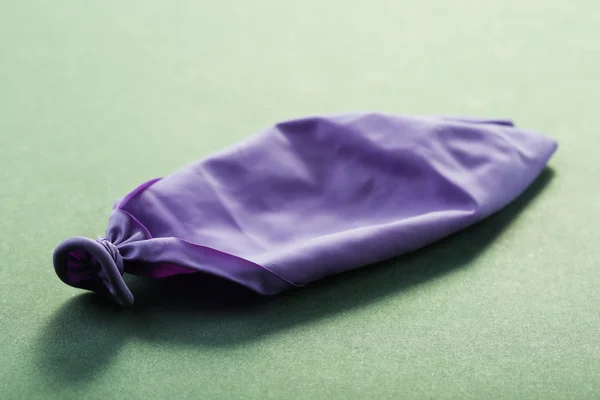 Popped violett ballong på papper bakgrund — Stockfoto
