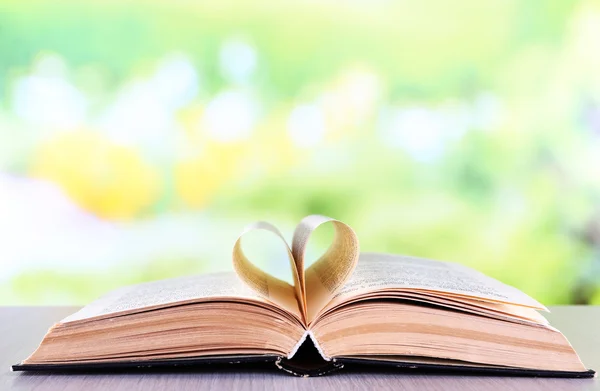 Open book on wooden table on natural background — Stock Photo, Image