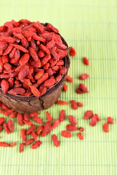 Goji berries in wooden bowl on bamboo mat background — Stock Photo, Image