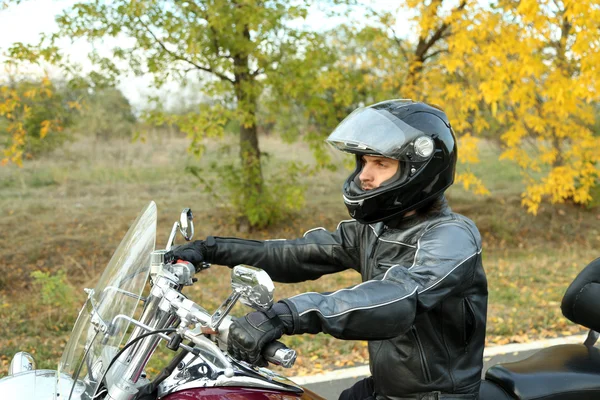 Biker uomo in casco nero si siede sulla moto — Foto Stock