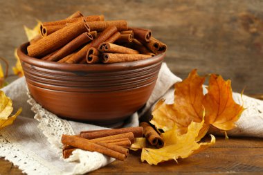 Ahşap zemin üzerine sarı yaprakları ile kase tarçın sopa