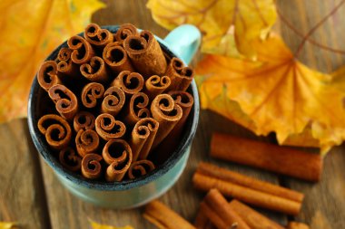 Ahşap zemin üzerine sarı yaprakları ile bardağa tarçın sopa