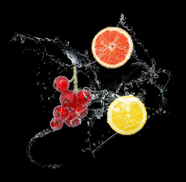 Frutas frescas en salpicaduras de agua, sobre fondo negro — Foto de Stock