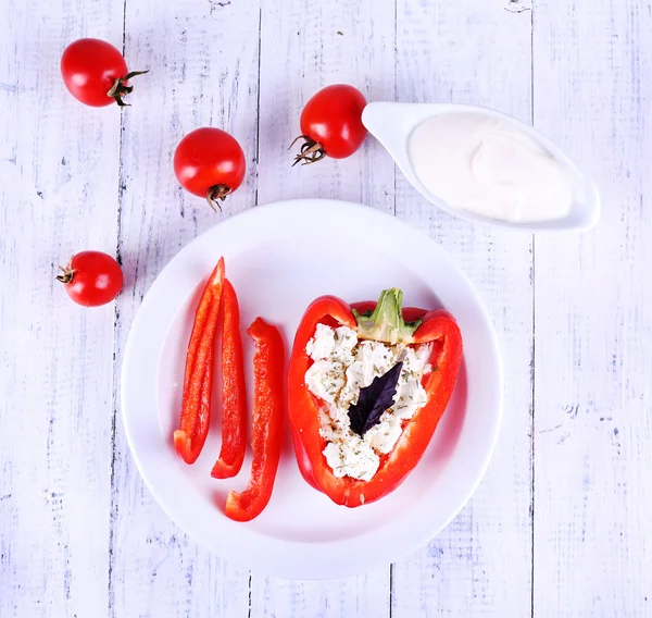 Pimenta recheada em prato, pires boat e tomates em fundo de madeira — Fotografia de Stock