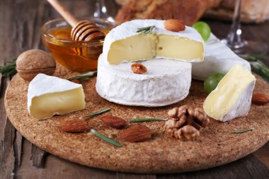 Kağıt, üzüm, fındık ve bal ahşap arka plan üzerinde kesme tahtası üzerinde üzerinde cam kapta Camembert peyniri