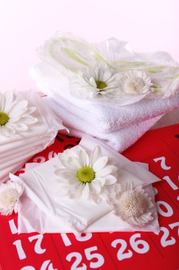 Hijyenik pedler ve pembe bir arka plan üzerinde kırmızı takvimde beyaz çiçekler