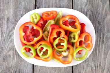 Ahşap arka plan üzerinde oval plaka üzerinde biber dilimlenmiş