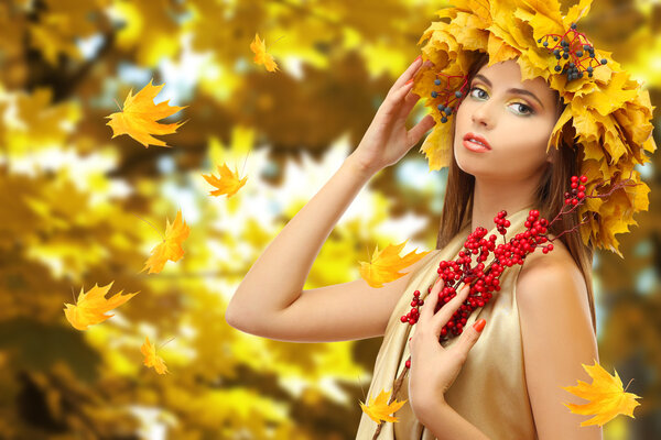 Beautiful young woman with yellow autumn wreath outdoors