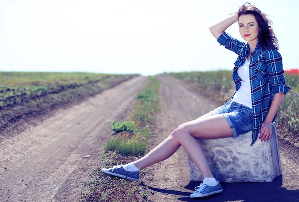 Mooie jonge vrouw zitten zit op koffer platteland onderweg — Stockfoto