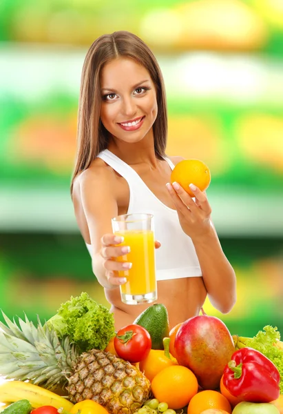 Concetto di shopping. Bella giovane donna con frutta e verdura e bicchiere di succo su sfondo negozio — Foto Stock