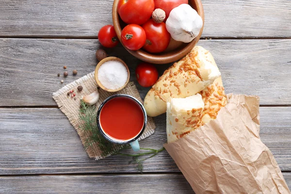 Sumo de tomate caseiro na caneca a cores, pães, especiarias e tomates frescos no fundo de madeira — Fotografia de Stock