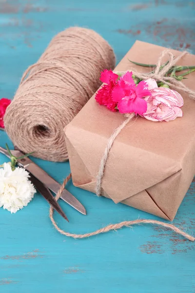 Hermoso regalo con flores y cuerda decorativa, sobre fondo de madera viejo —  Fotos de Stock