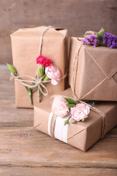 Prachtige geschenken met bloemen, op oude houten achtergrond — Stockfoto