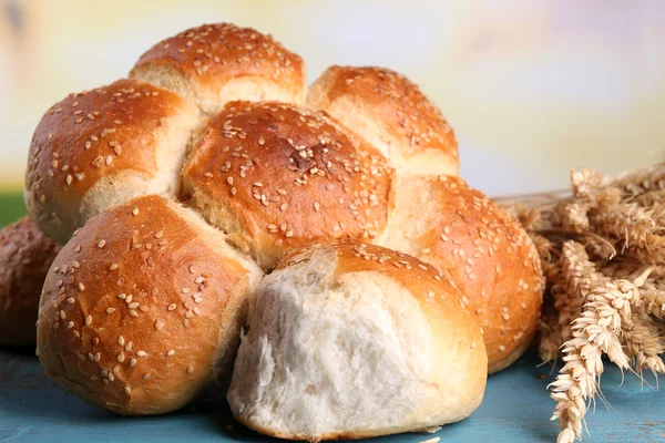 Goda bullar med Sesam på trä färgtabell på ljus bakgrund — Stockfoto