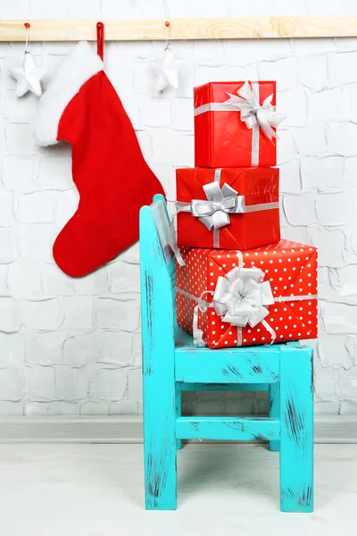 Cadeaux de Noël sur chaise bleue sur fond de mur de briques — Photo