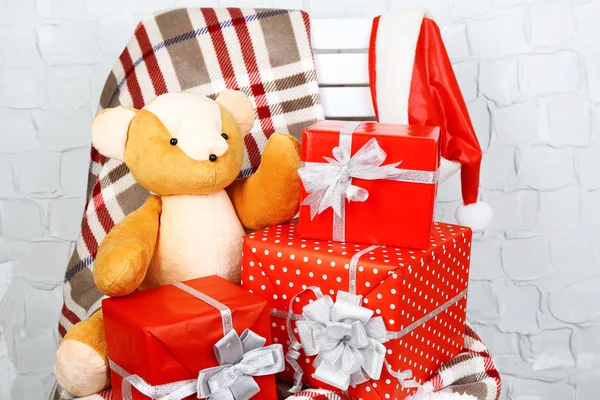 Weihnachtsgeschenke auf Decke auf weißem Stuhl auf Backsteinwand Hintergrund — Stockfoto